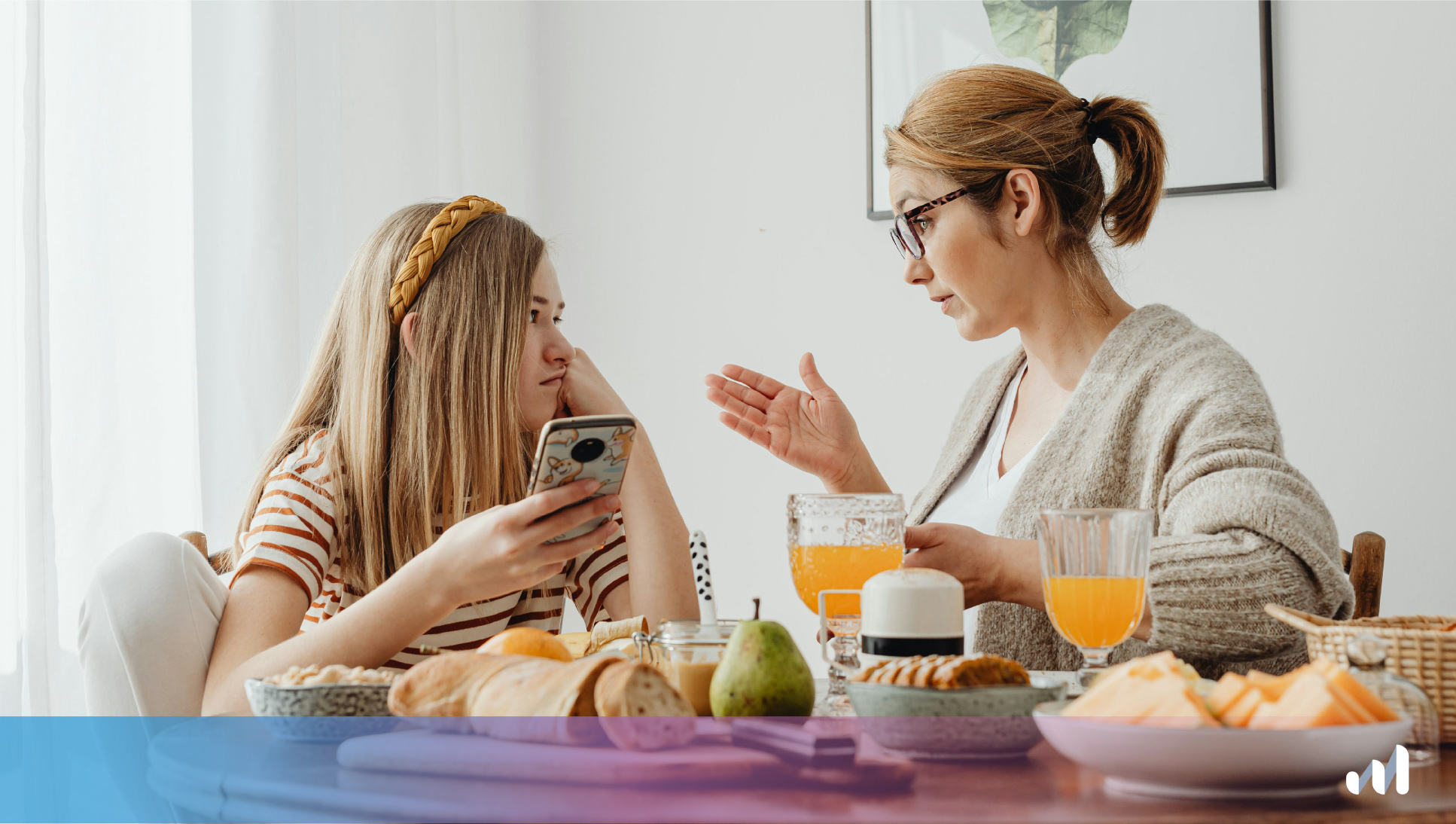mère et fille tenant son portable qui discutent à table