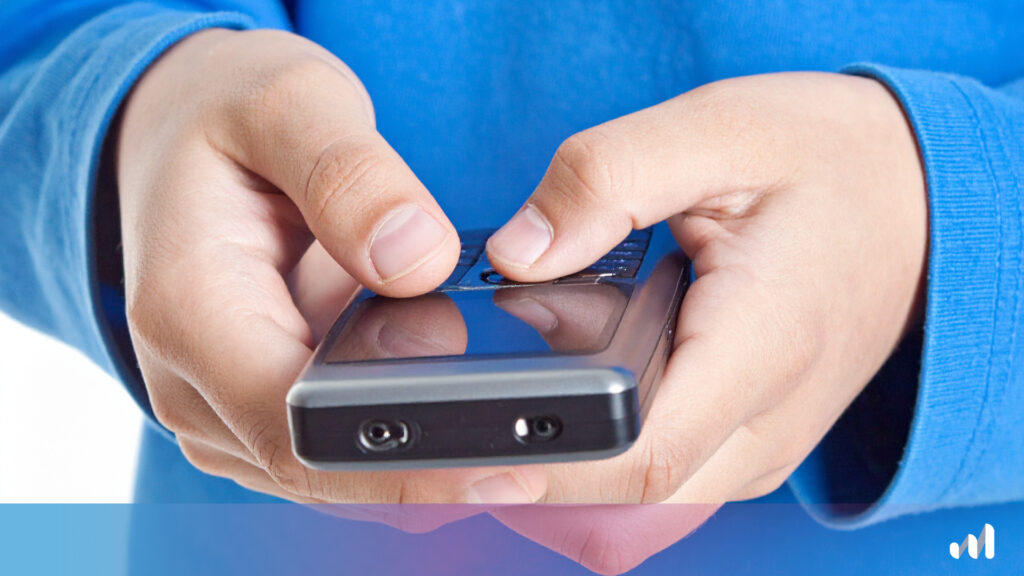 enfant qui tient un dumb phone dans les mains
