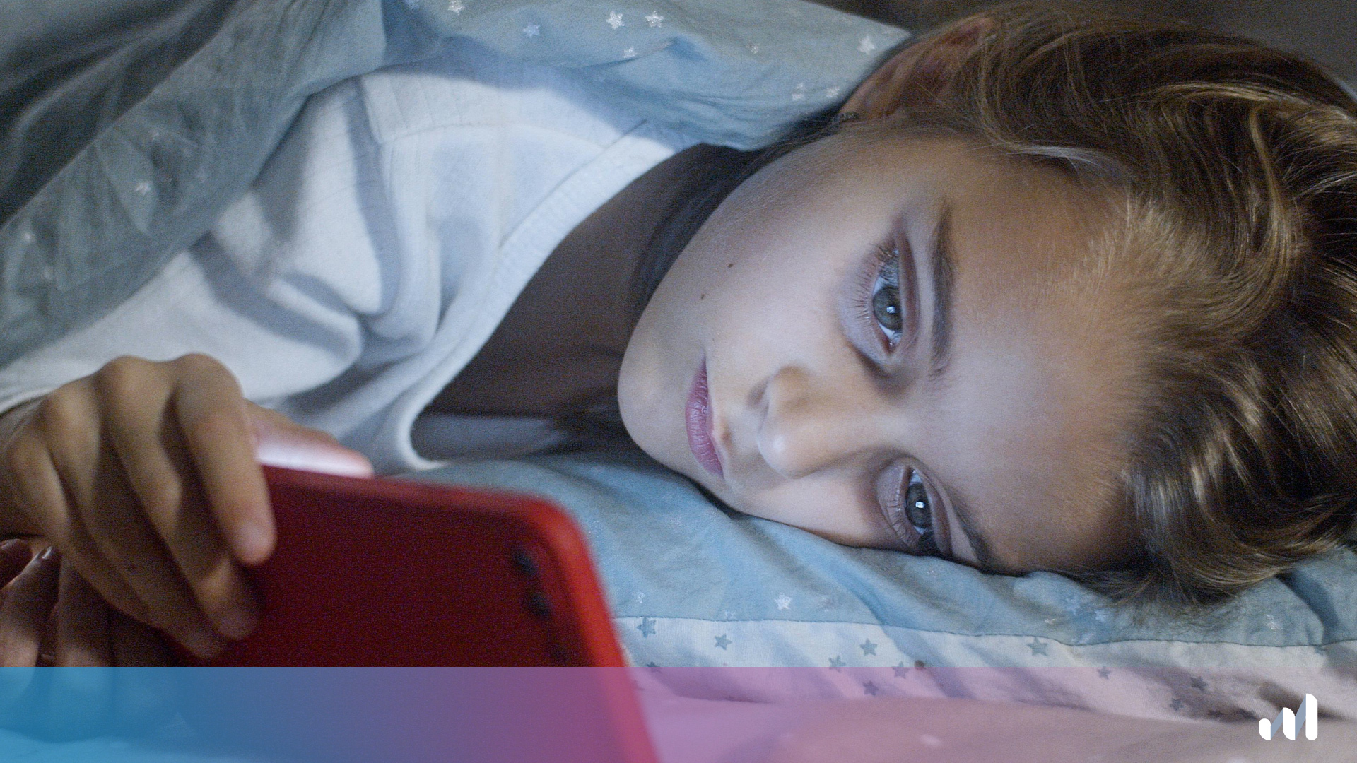 enfant qui regarde son téléphone allongée